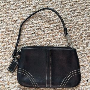 Coach wristlet in black with zip top and white stitch details.